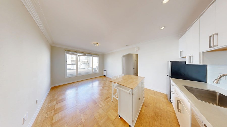 A kitchen with a wooden floor and white cabinets.